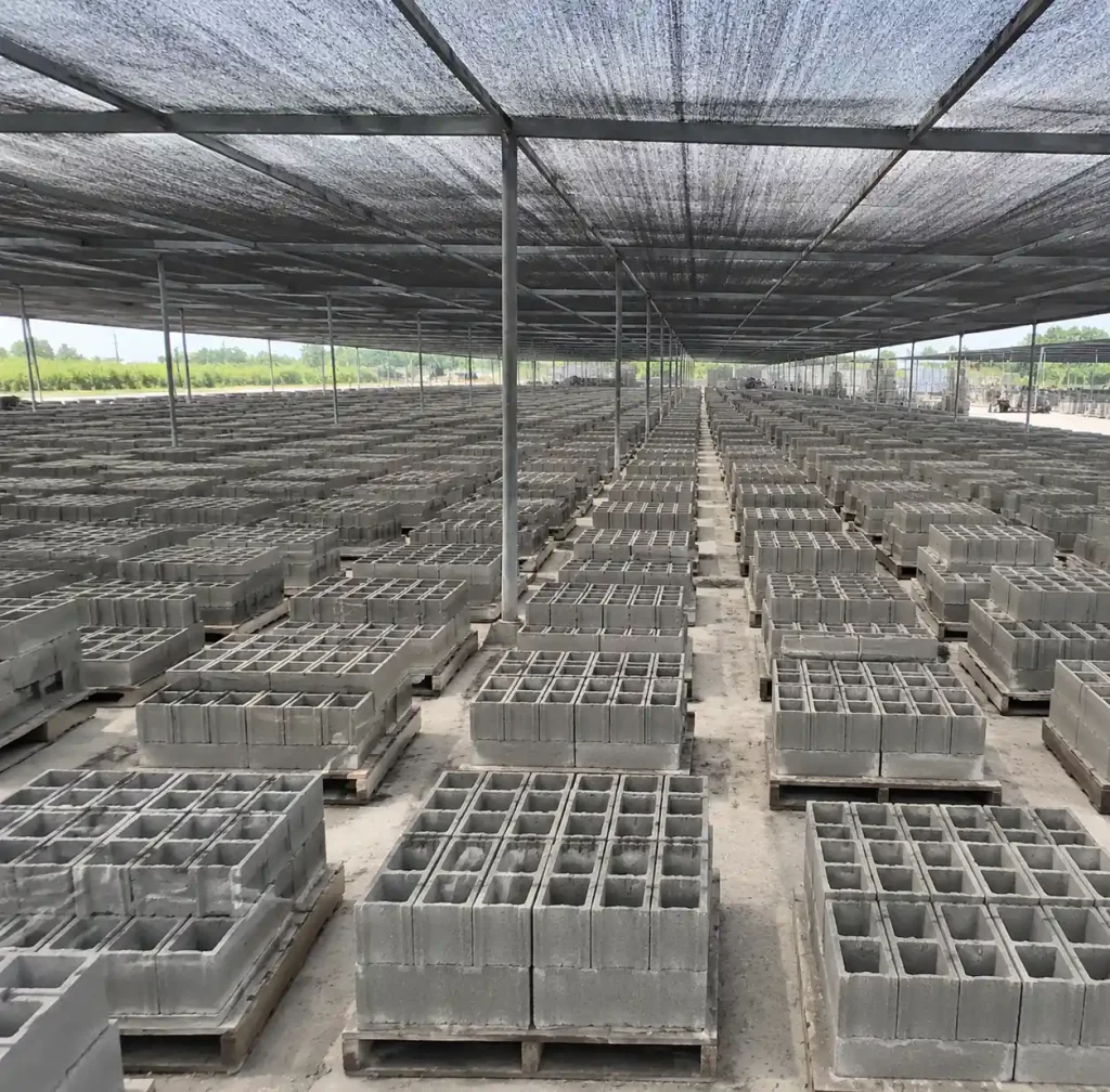 Concrete blocks curing in organized rows with shade protection