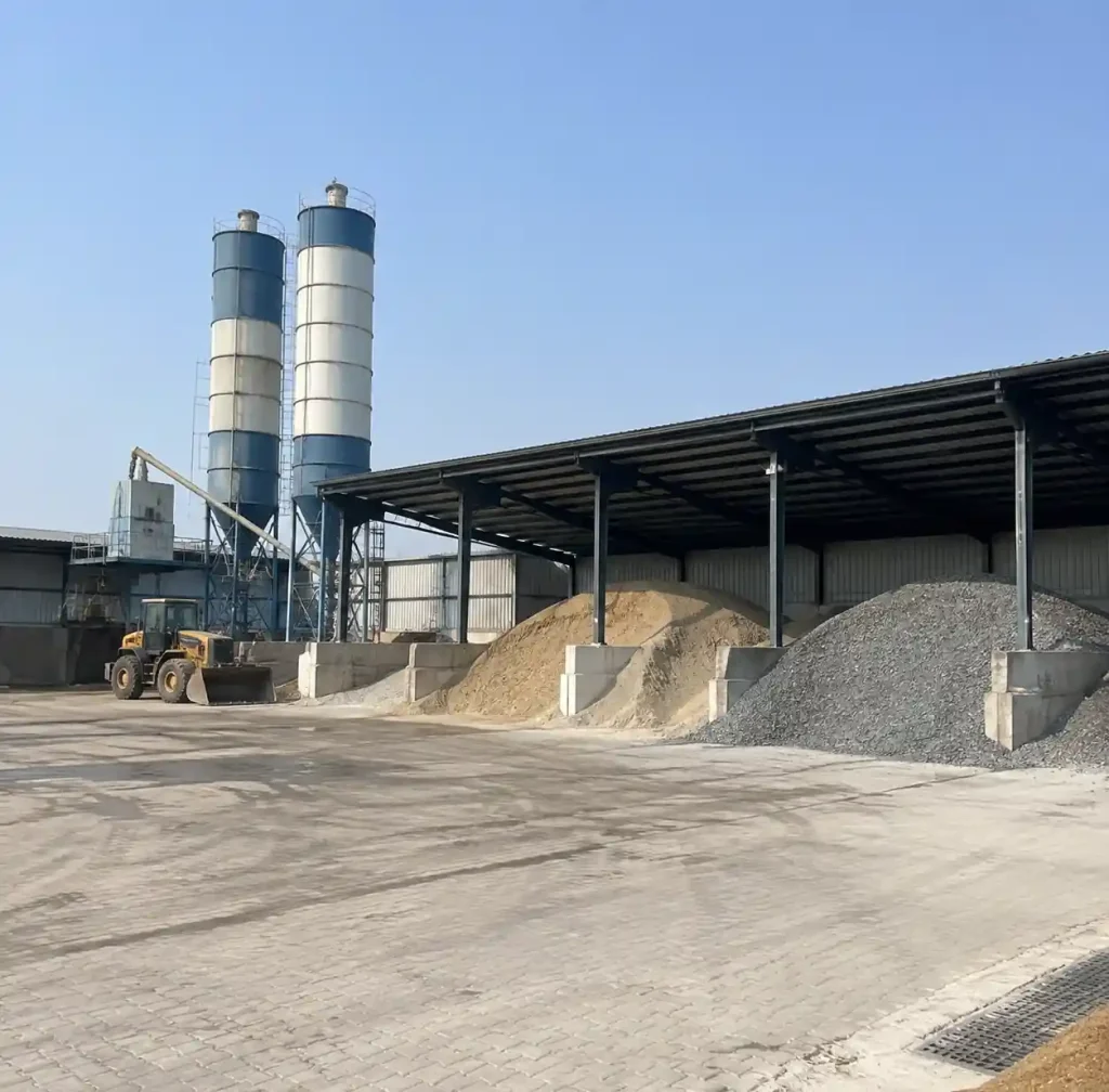 Raw material storage zone with cement silos and aggregate stockpiles for block production