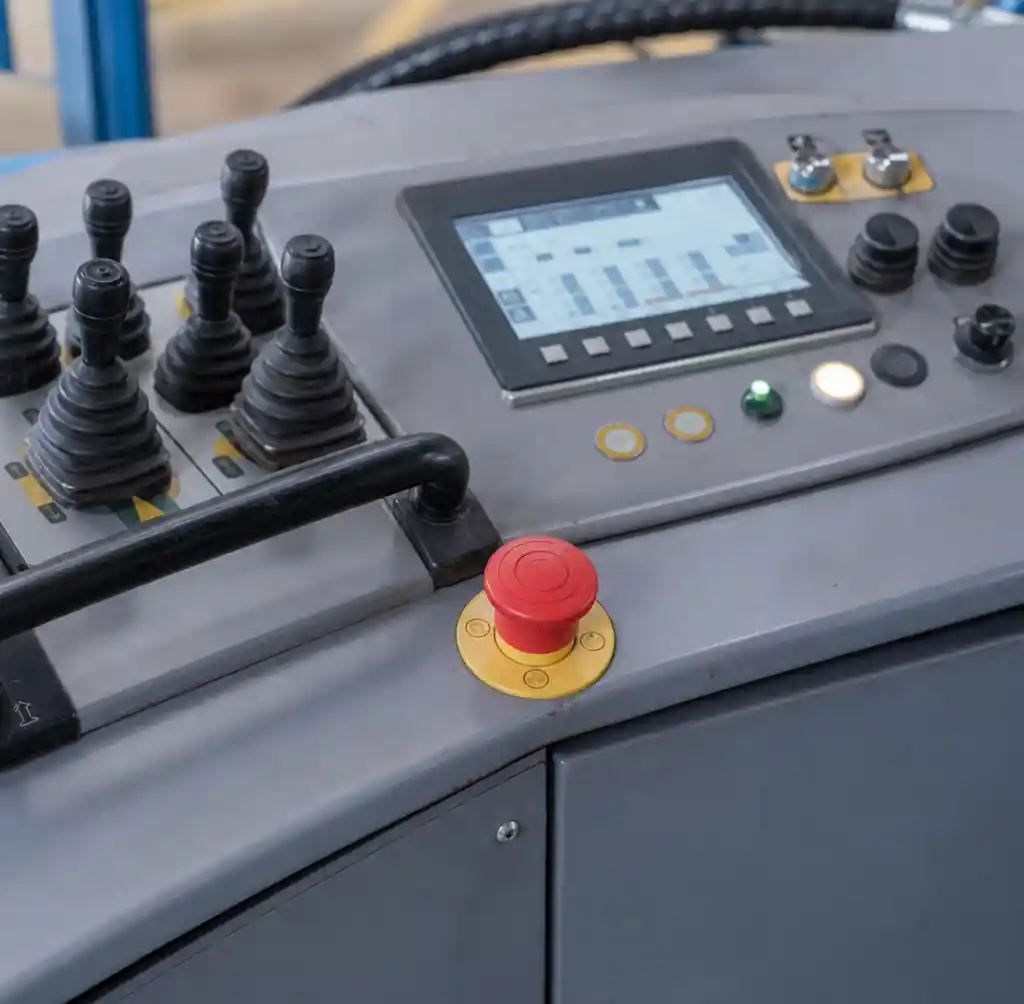 Red emergency stop button prominently positioned on block making machine control panel